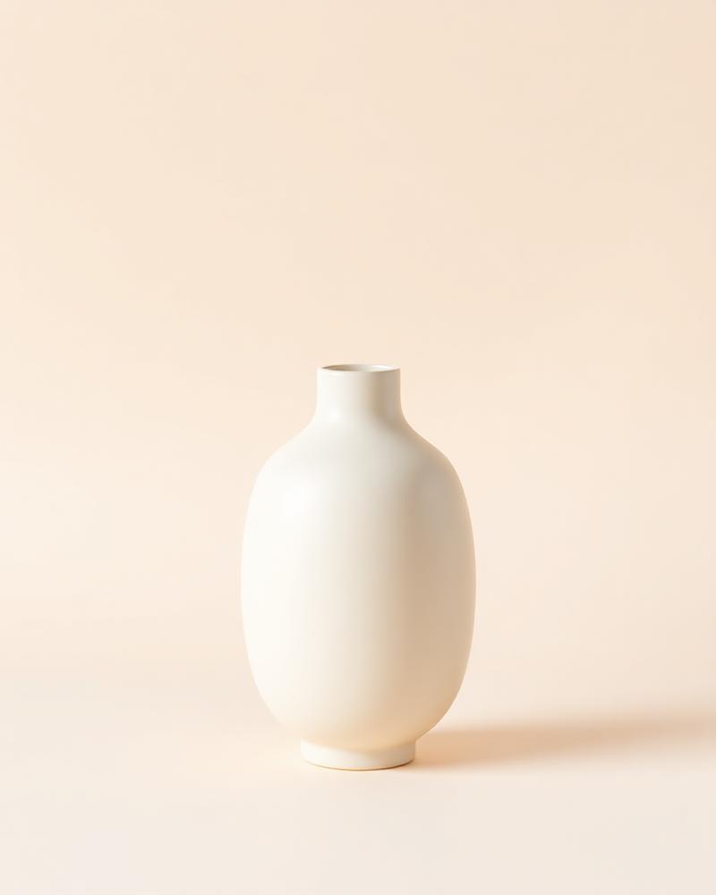 Ribbed stoneware stem vase in a soft matte glaze on a plain neutral background